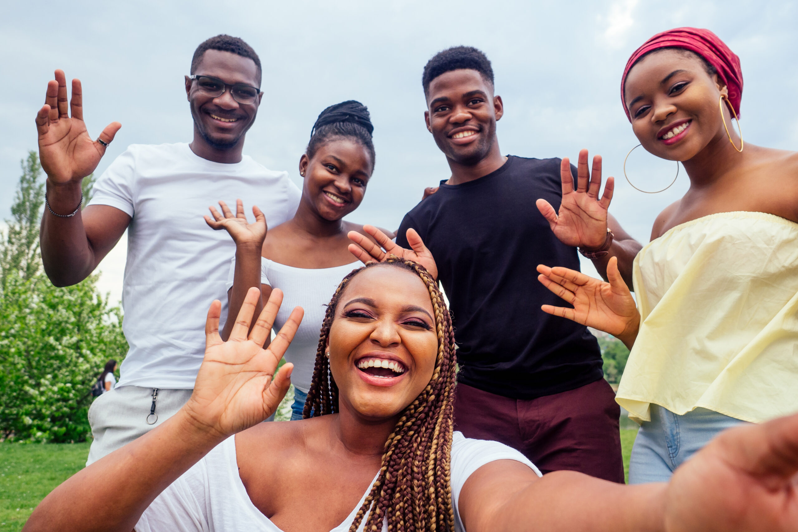 group of five friends female and male taking selfie on camera smartphone and having fun outdoors lifestyle near lake